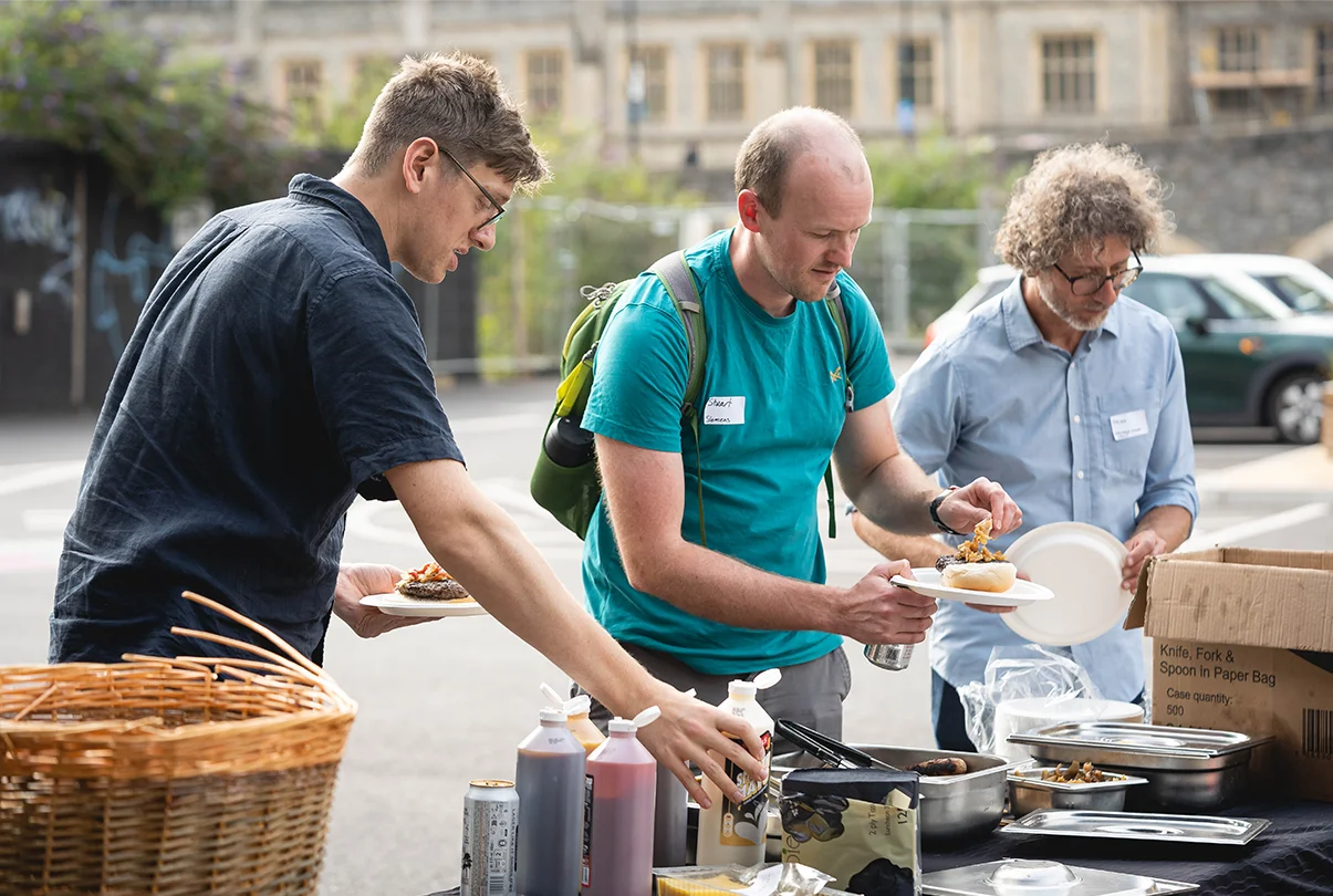 a group of men standing next to a table with food
