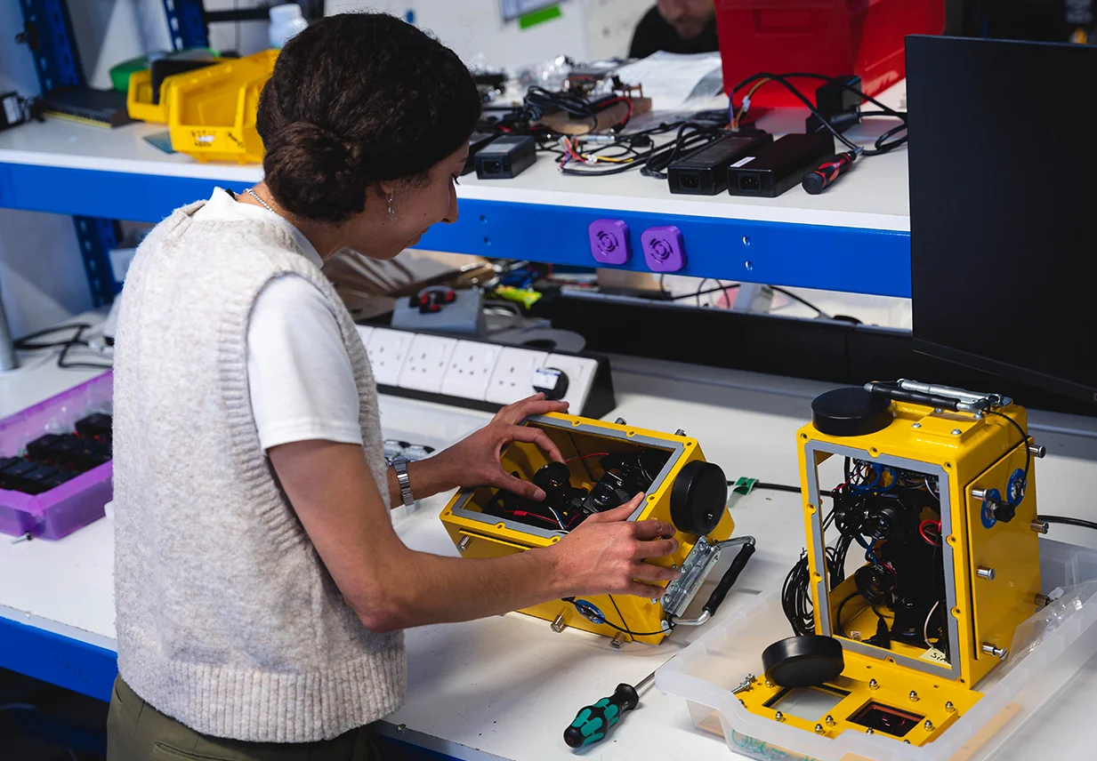 One Big Circle employee assembling monitoring device in lab.