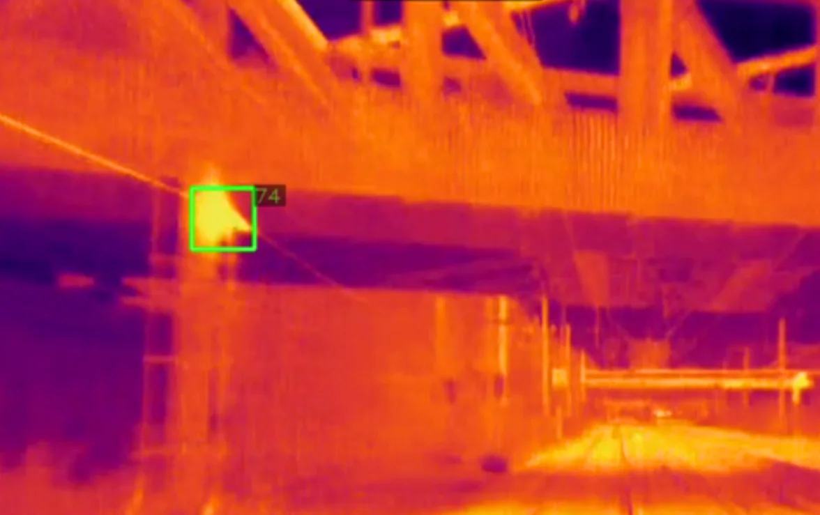 Thermal camera image of overhead line equipment showing a highlighted hotspot detection.
