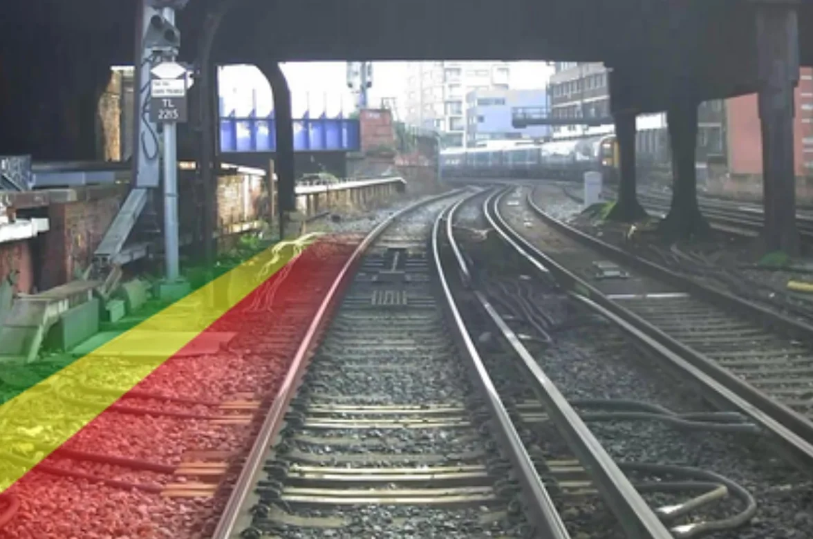 Forward-facing video from the AIVR Platform showing a station approach with safe cess overlay in green, yellow, and red indicating proximity to the track.