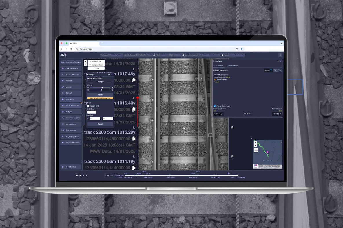 Laptop screen showing the AIVR Platform interface with a black-and-white line-scan image of railway track in the centre, a detections panel on the right listing a flagged crossing, and a route map.