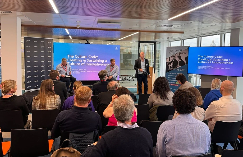 A speaker standing and two seated panellists present to an audience, beneath a slide reading “The Culture Code: Creating and Sustaining a Culture of Innovativeness”.